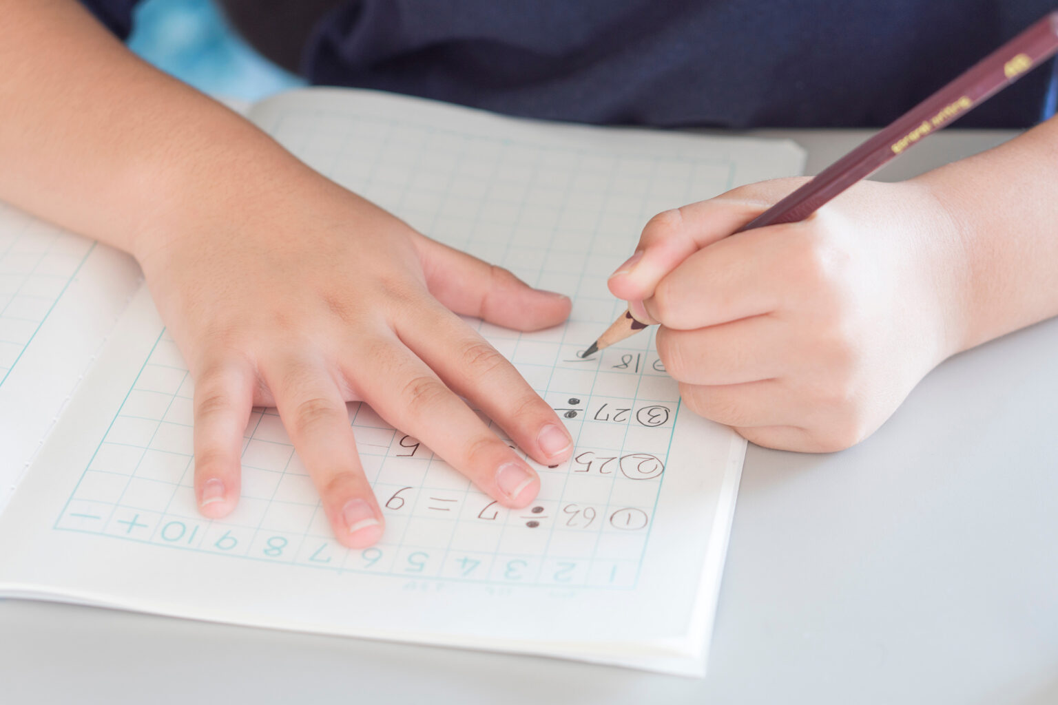 Ein Linkshänder erarbeitet Matheaufgaben in seinem Arbeitsheft